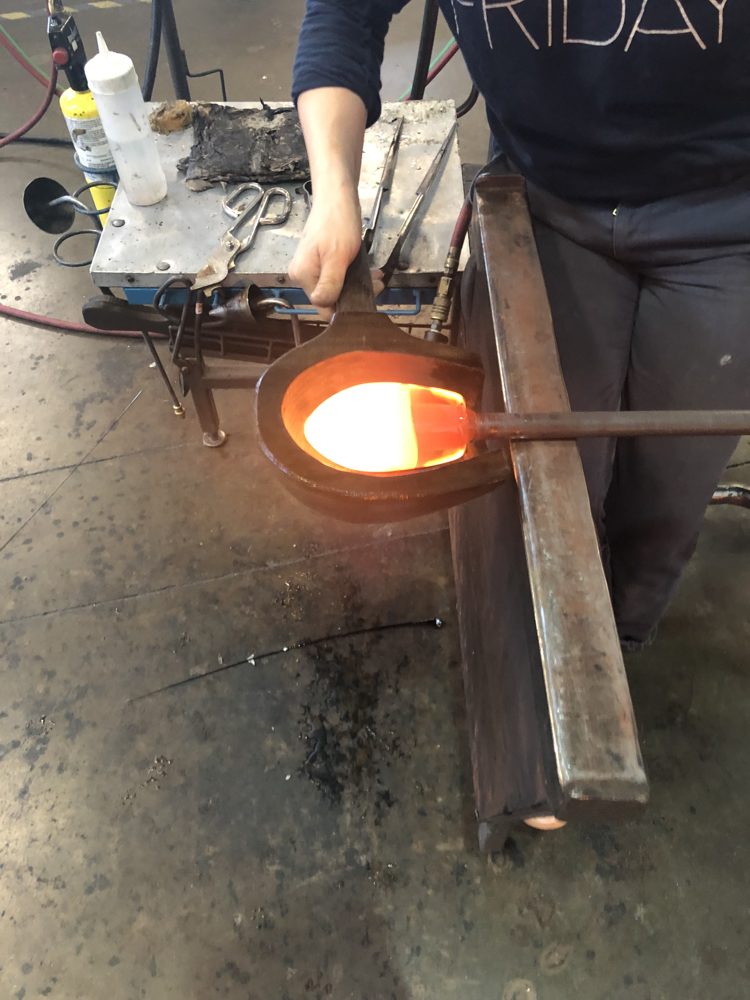 Shaping a glowing piece of molten glass at the bench