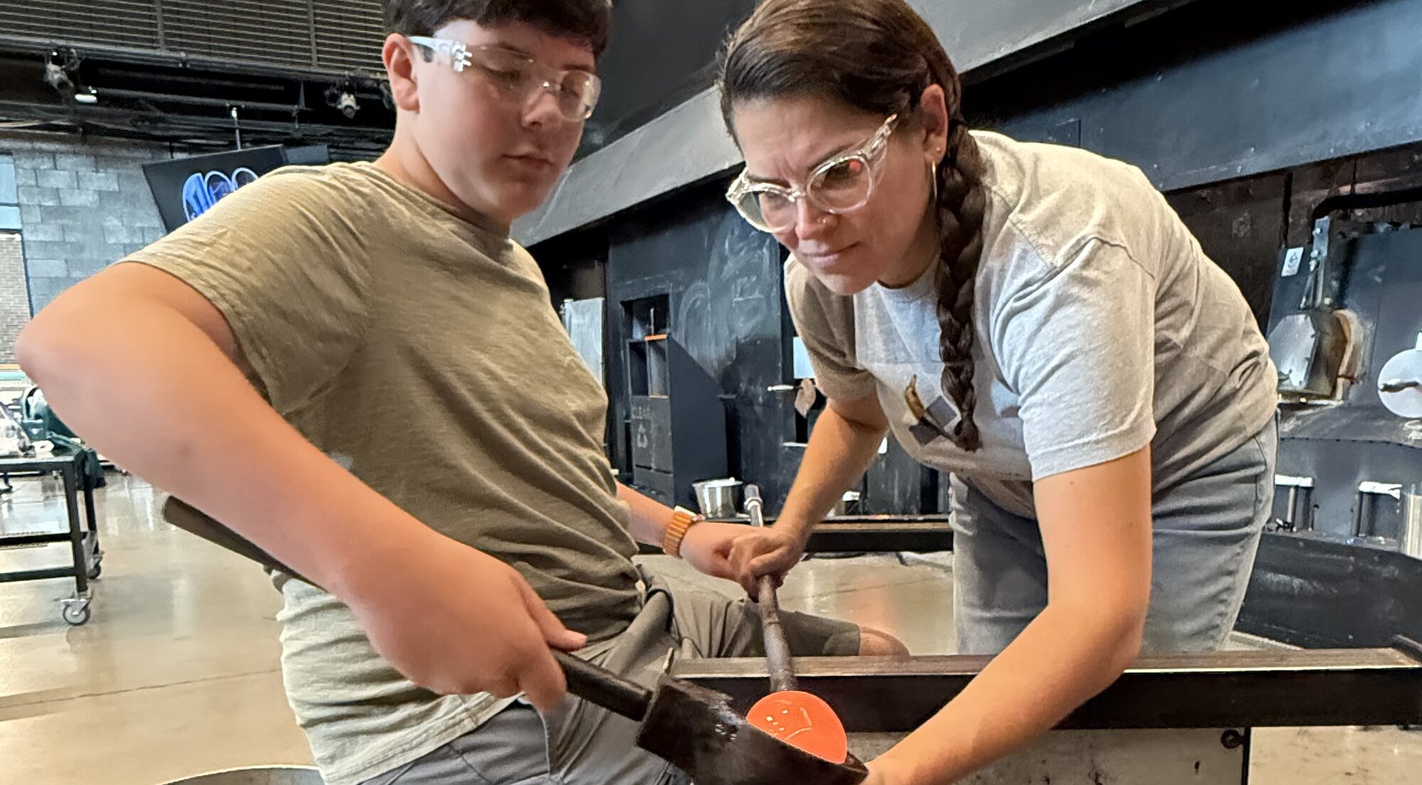 Kim teaching a student glassblowing