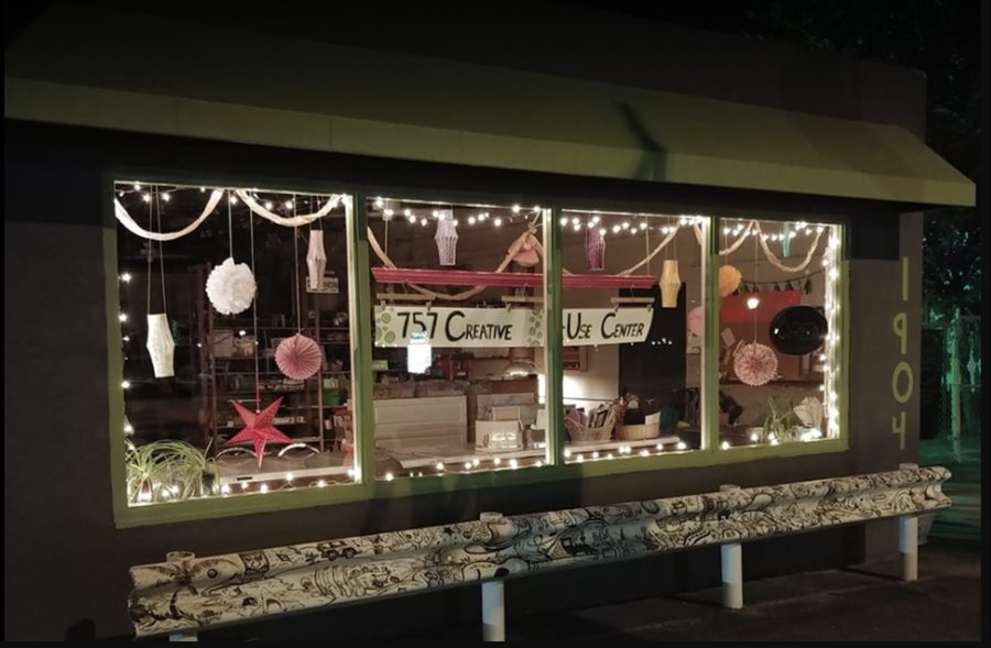 The 757 Creative ReUse Center storefront at night, lit with string lights and a hand-painted sign